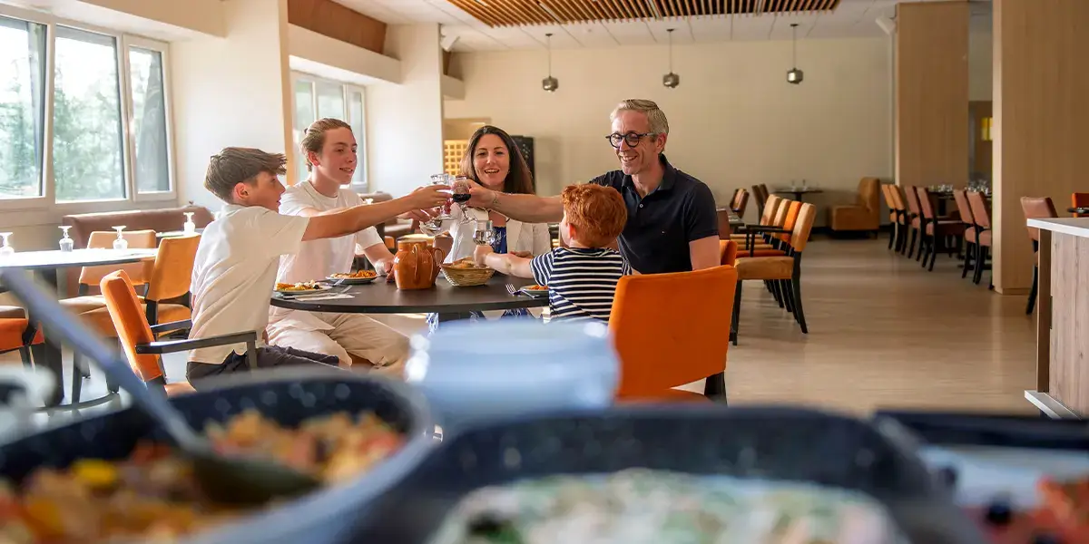 Une famille qui profite de la pension complète dans le restaurant d'un village vacances VTF