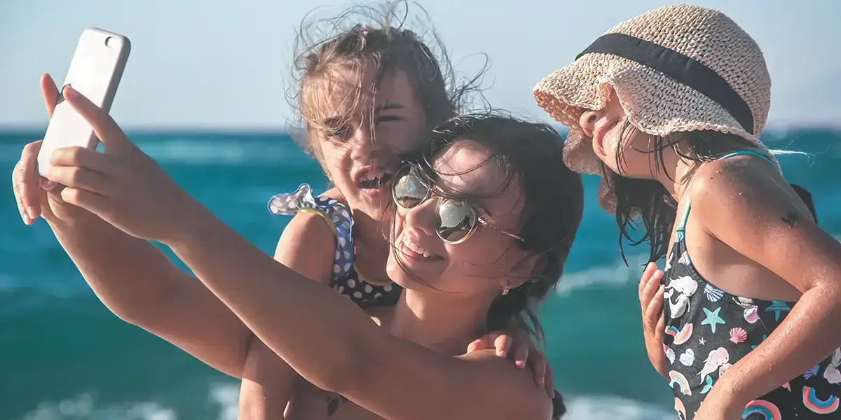 Maman avec ses 2 enfants prenant un selfie sur la plage en vacances à la mer avec VTF