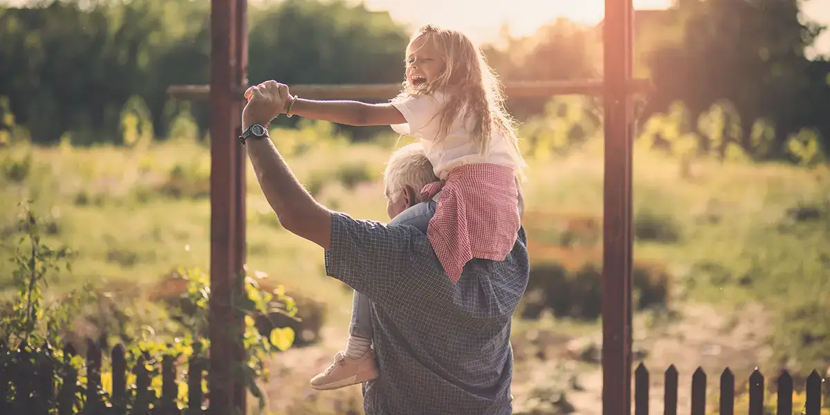 Petite fille sur les épaules de son grand-père en village vacances VTF