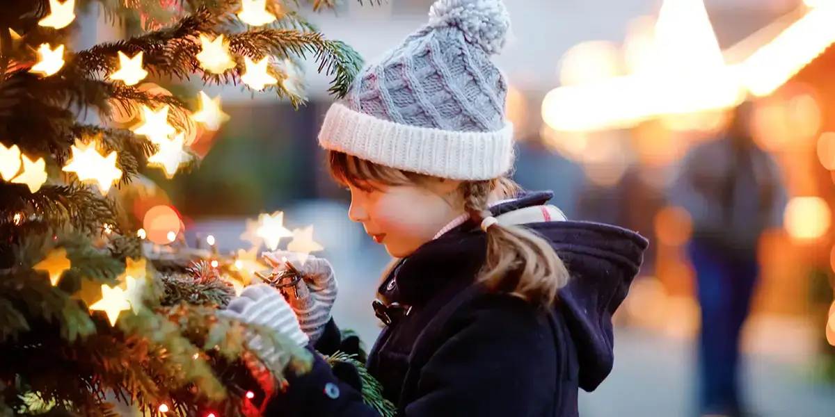 Une enfant joue avec le sapin pendant les vacances de Noël et Nouvel An