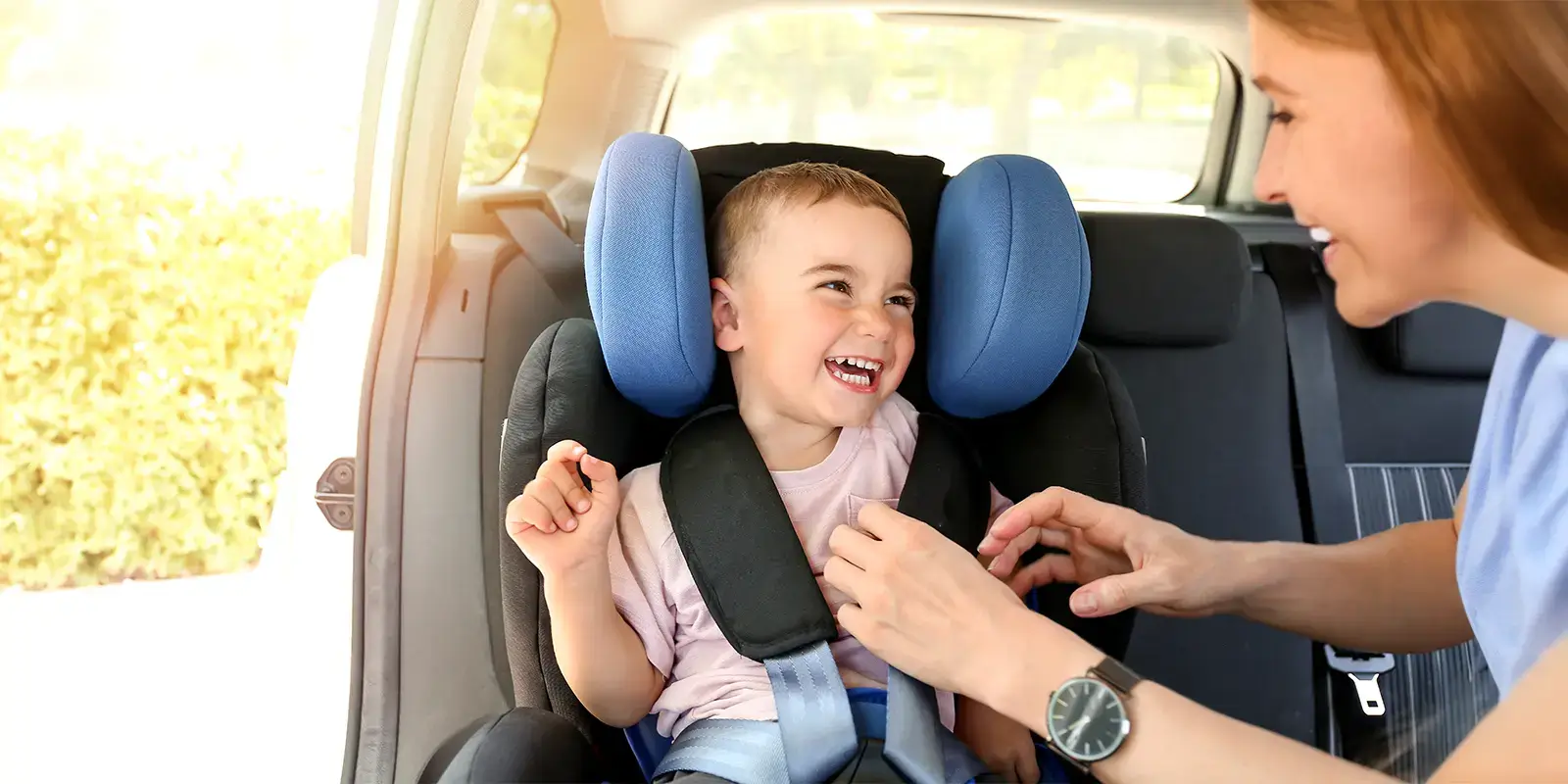 Maman installant son enfant dans la voiture pour partir en village vacances VTF