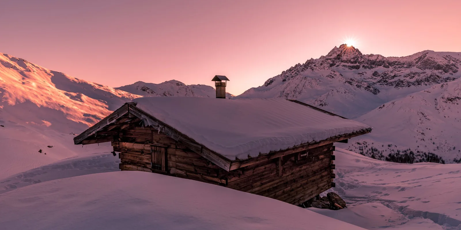 Chalet en bois sous la neige au coucher du soleil dans les Alpes du Sud
