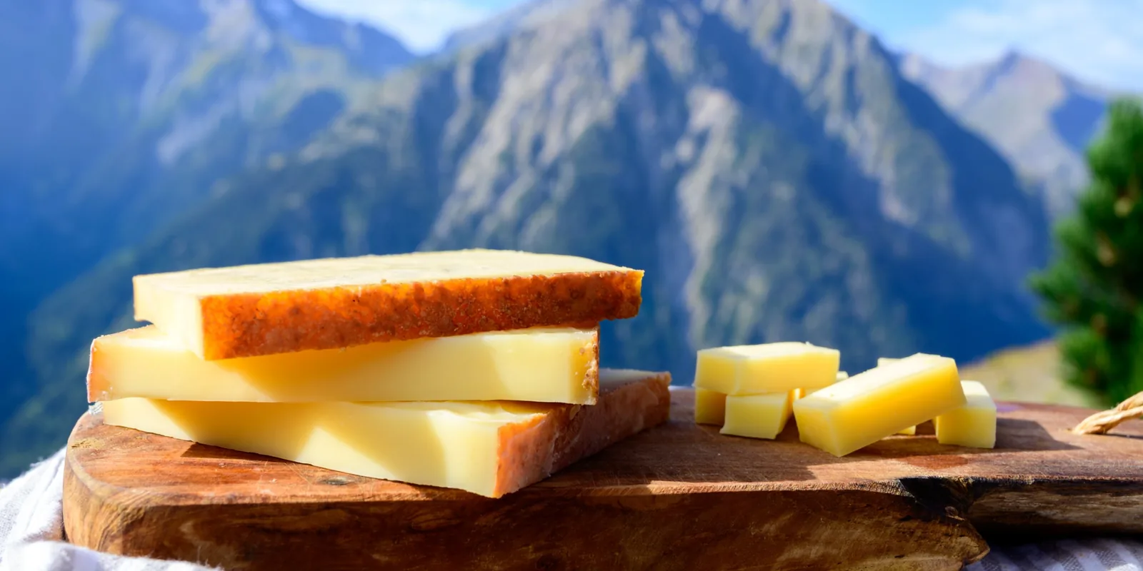 Fromages de montagne AOP sur une planche en bois face aux sommets