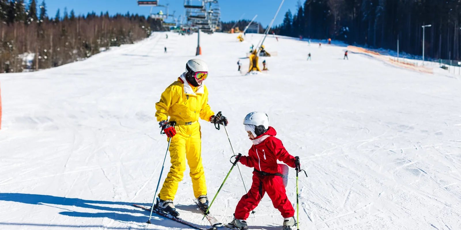 Maman et enfant au ski sur une piste ensoleillée