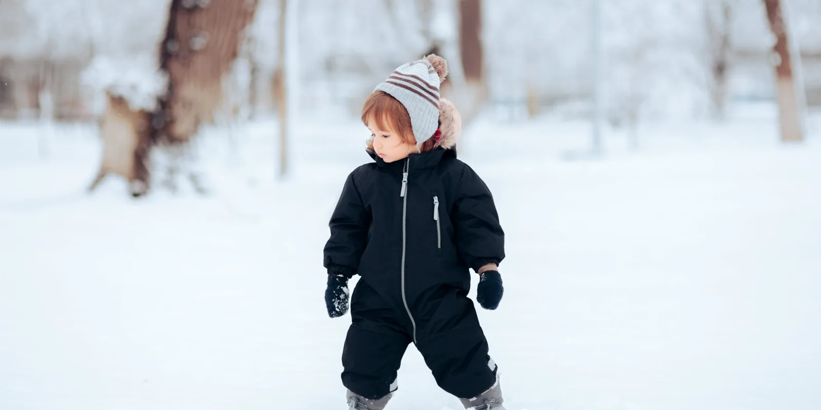 Tout-petit en combinaison de ski qui découvre la neige