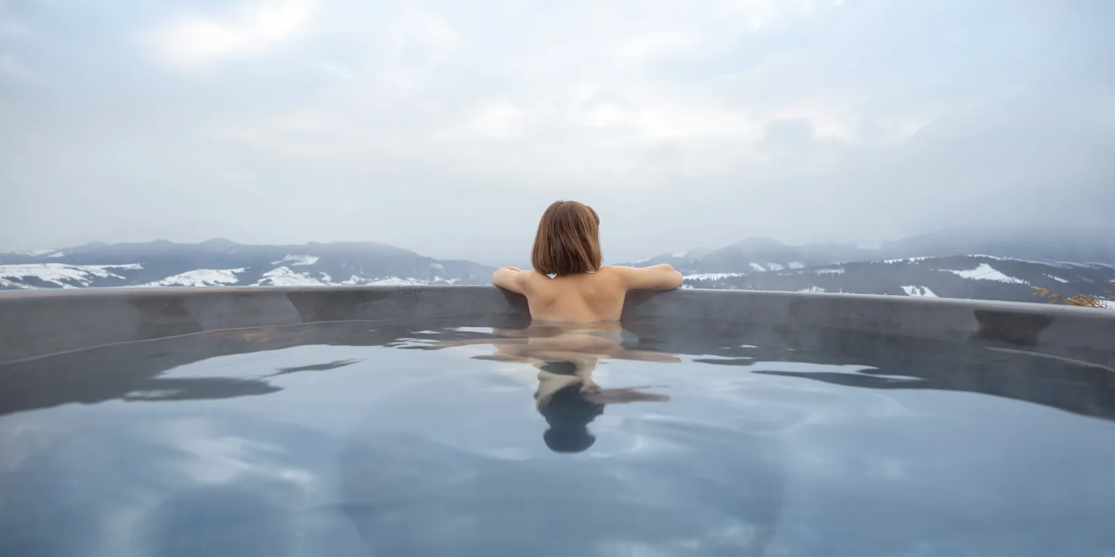 Bain chaud en plein air avec vue sur les montagnes enneigées