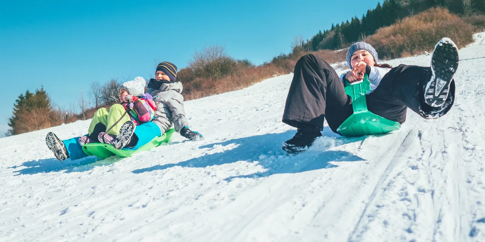 Famille qui profite d'une descente en luge pendant ses vacances au ski